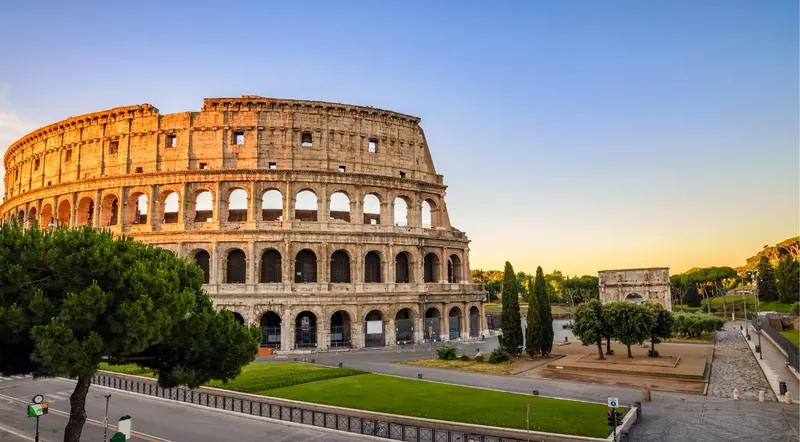 The Colosseum and Arch of Constantine at sunrise under a clear sky
