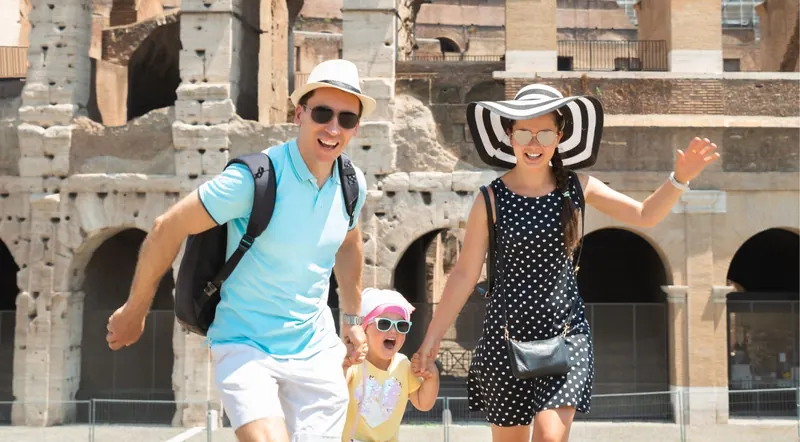 Parents and daughter walking joyfully in front of the Colosseum on a sunny day