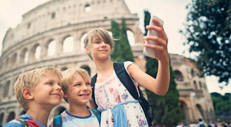 Three children taking a selfie in front of the Colosseum